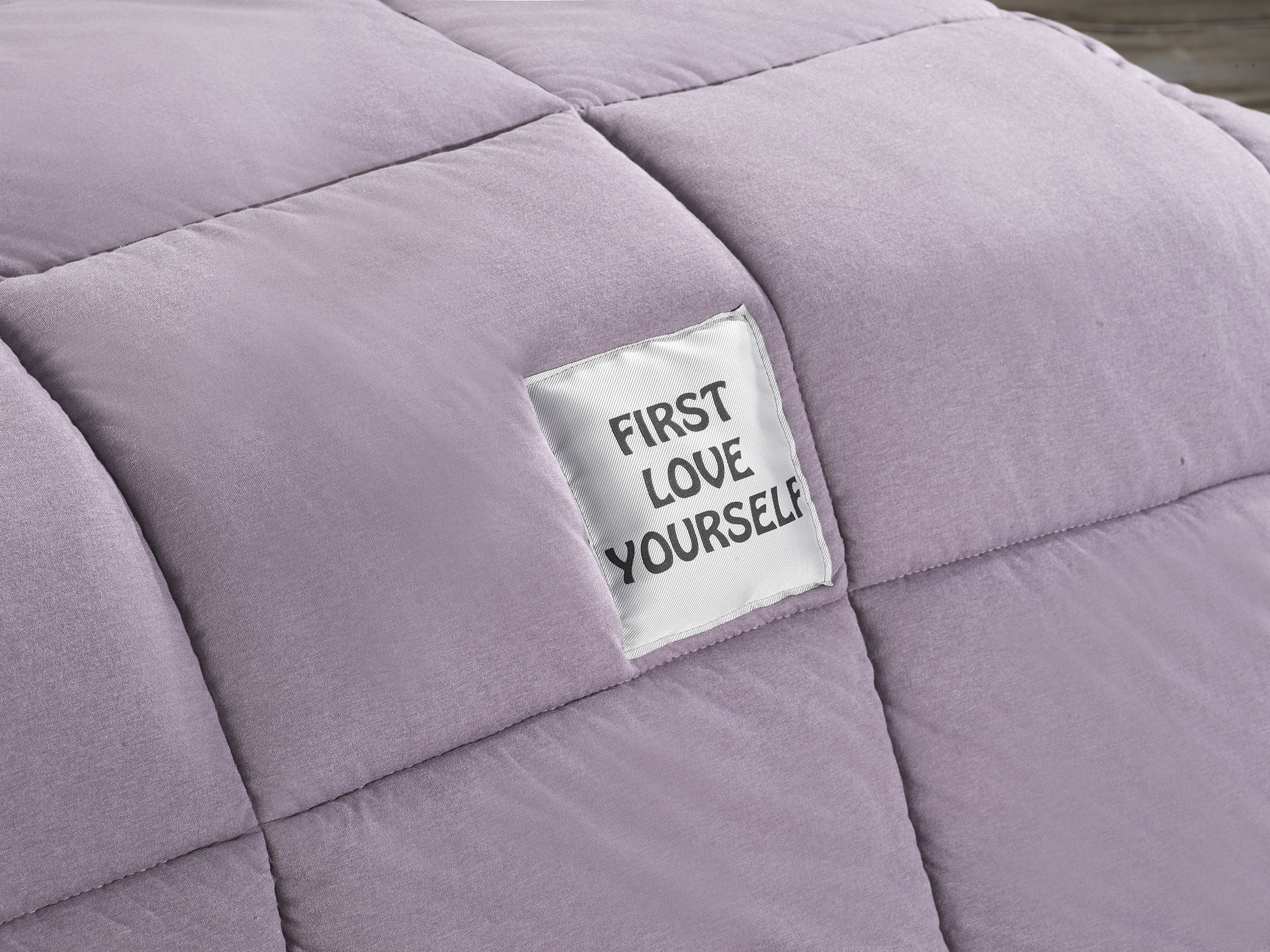Purple quilt with a 'First Love Yourself' tag Embroidered on the quilt