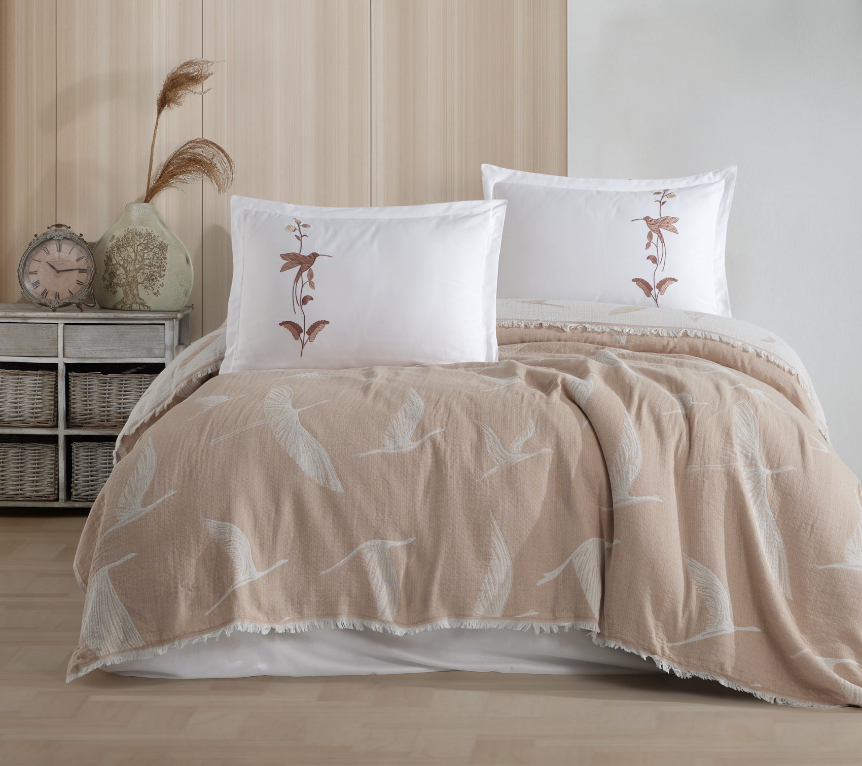 Beige and white bedding set with floral patterns on a bed in a bedroom setting.