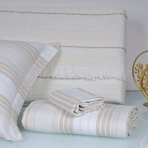 Beige and white striped bedding set on a bed with a decorative headboard.