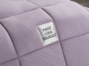 Purple quilt with a 'First Love Yourself' tag Embroidered on the quilt