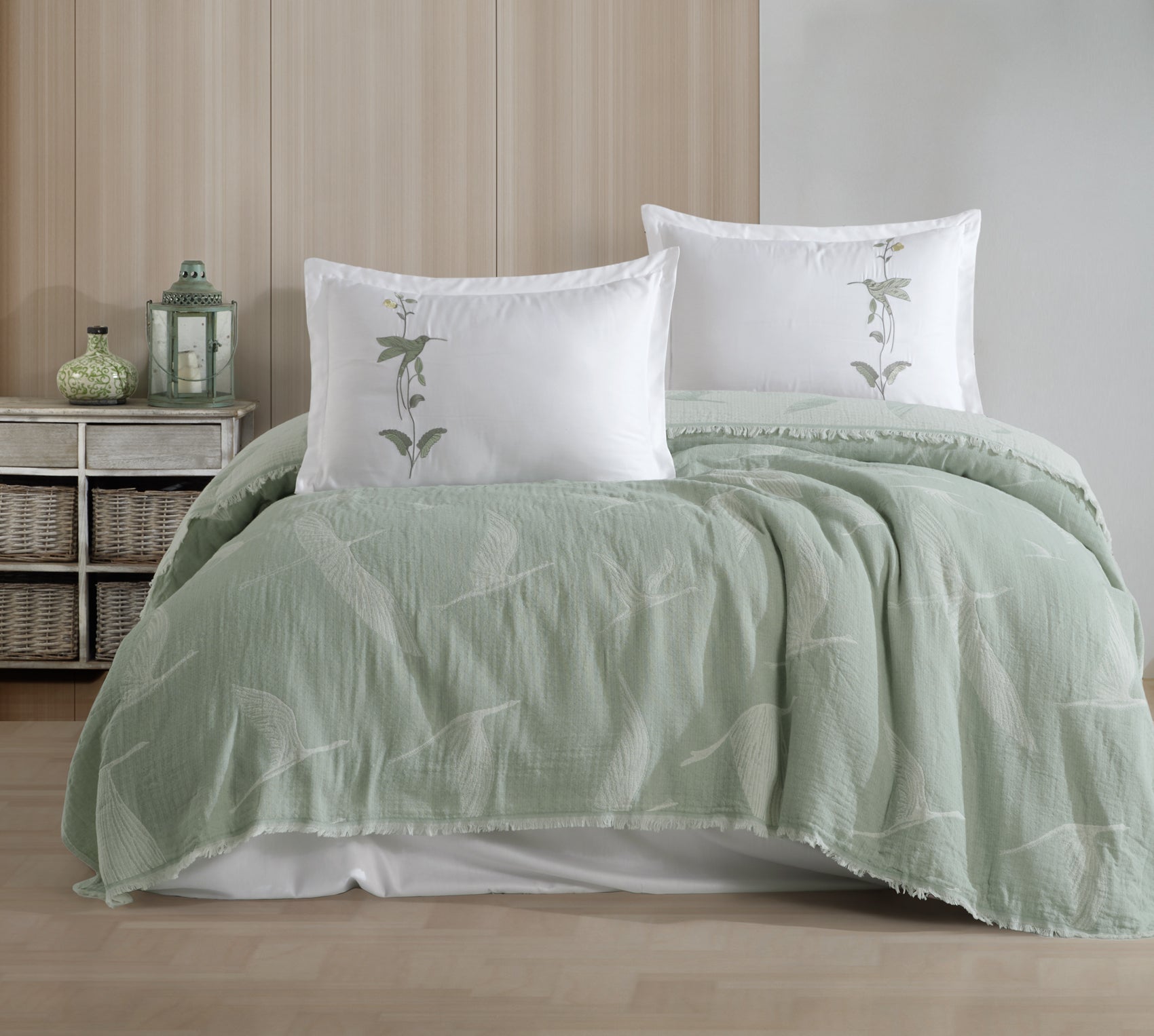 Green textured comforter and pillows on a bed in a bedroom setting.