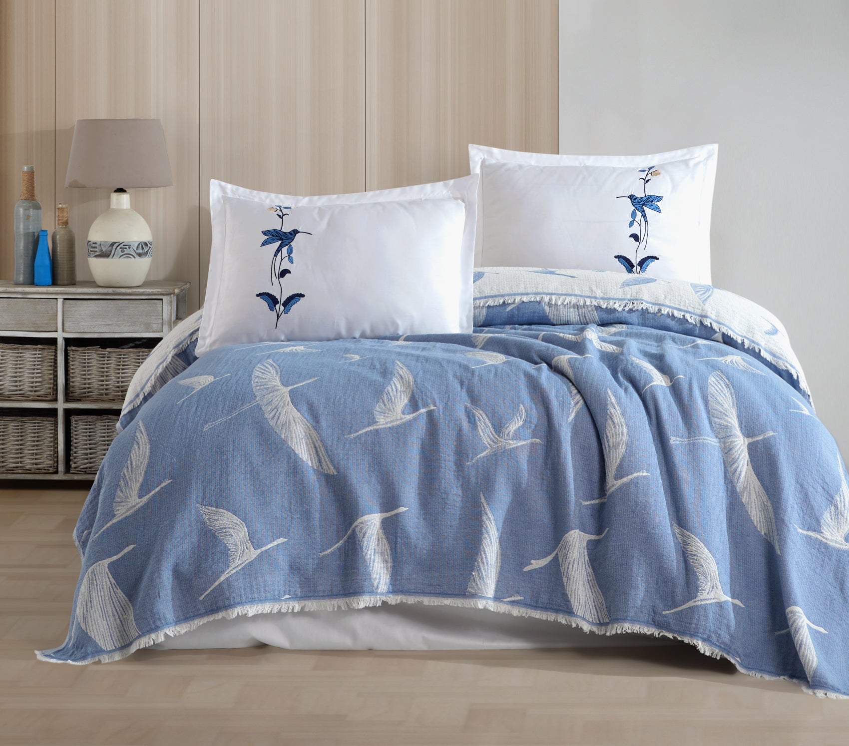 Blue quilt with bird patterns and white pillows in a bedroom 