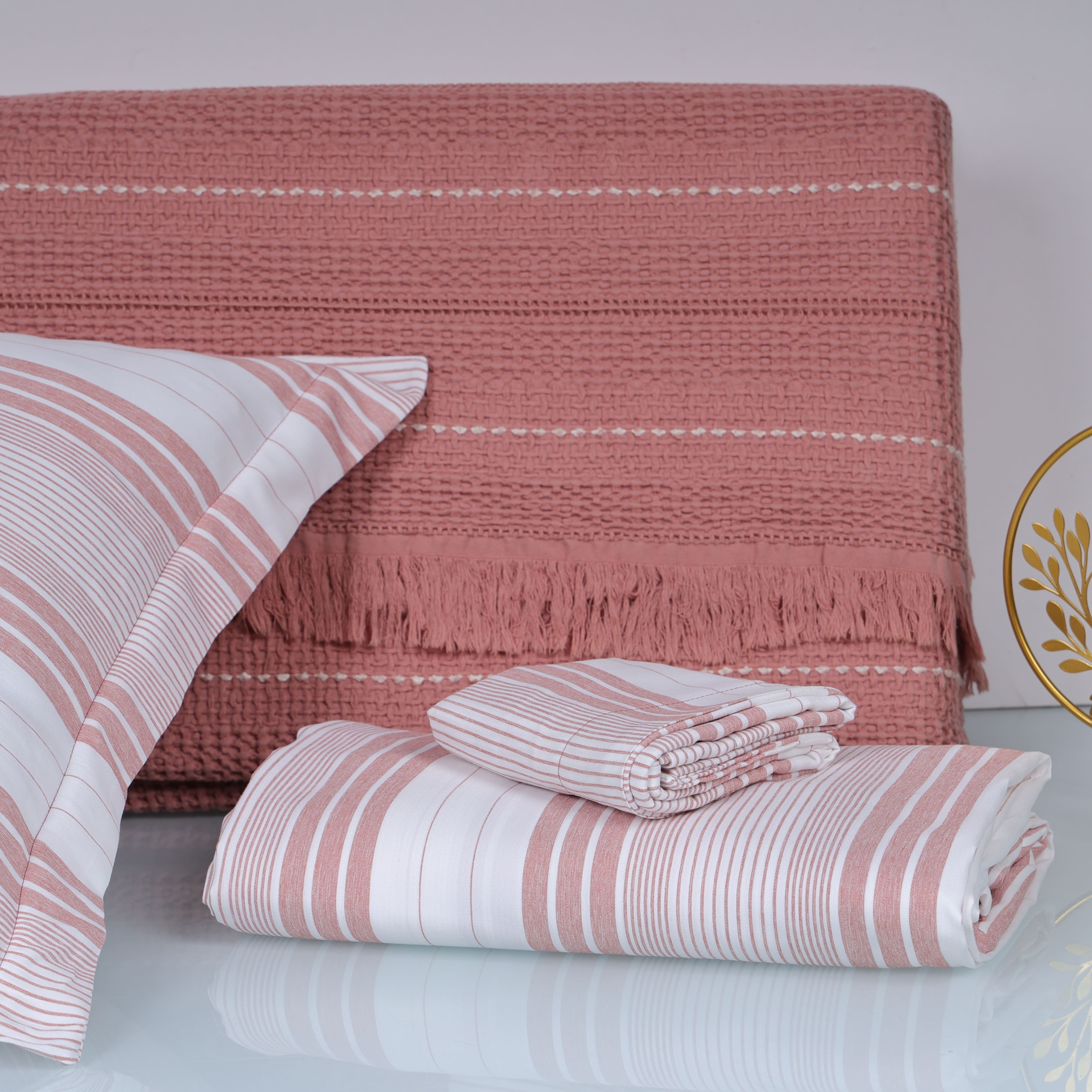 Pink and white striped bedsheey on a bed with a matching headboard