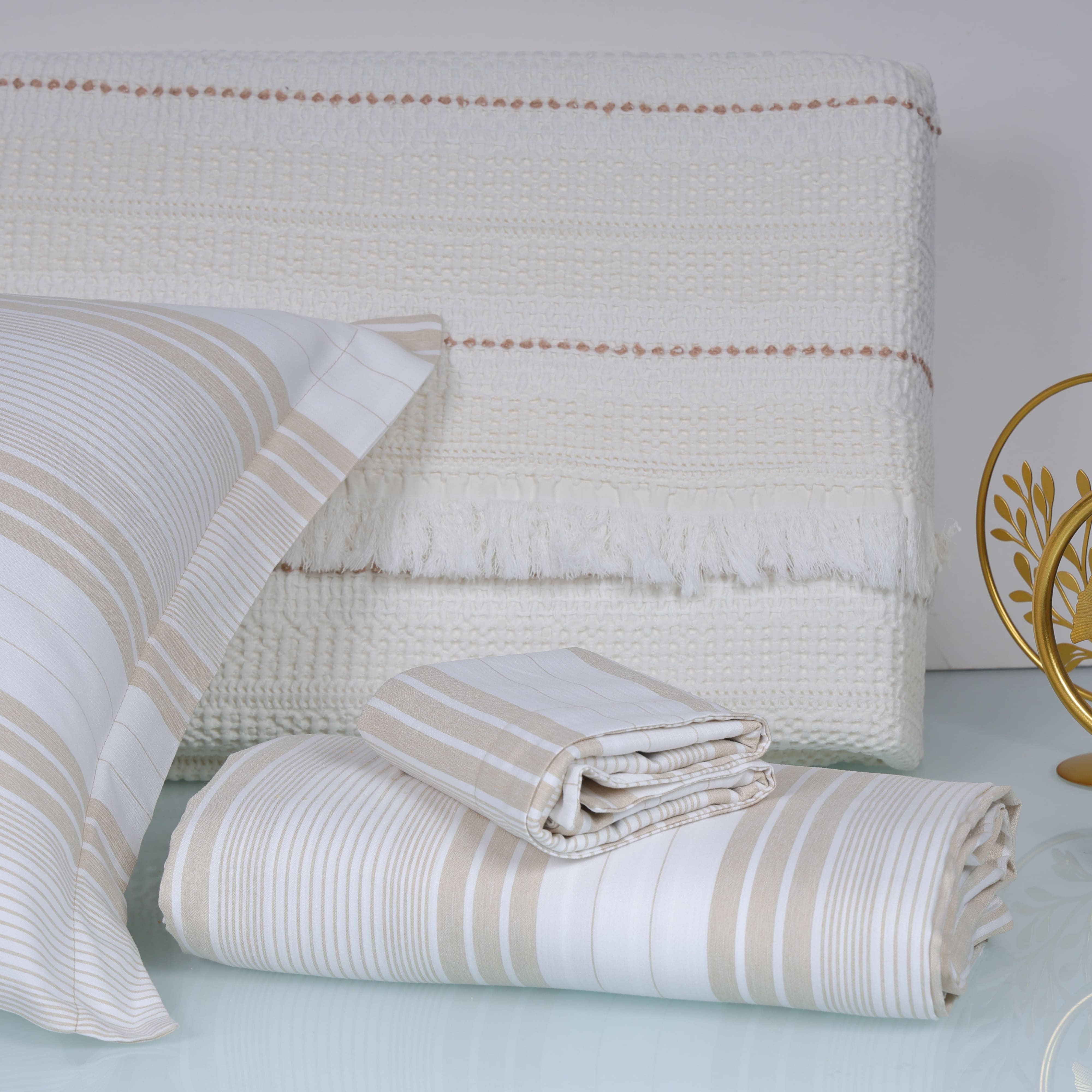 Beige and white striped bedding set on a bed with a decorative headboard.