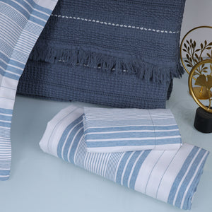 Blue and white striped bedsheet with a textured blue blanket 