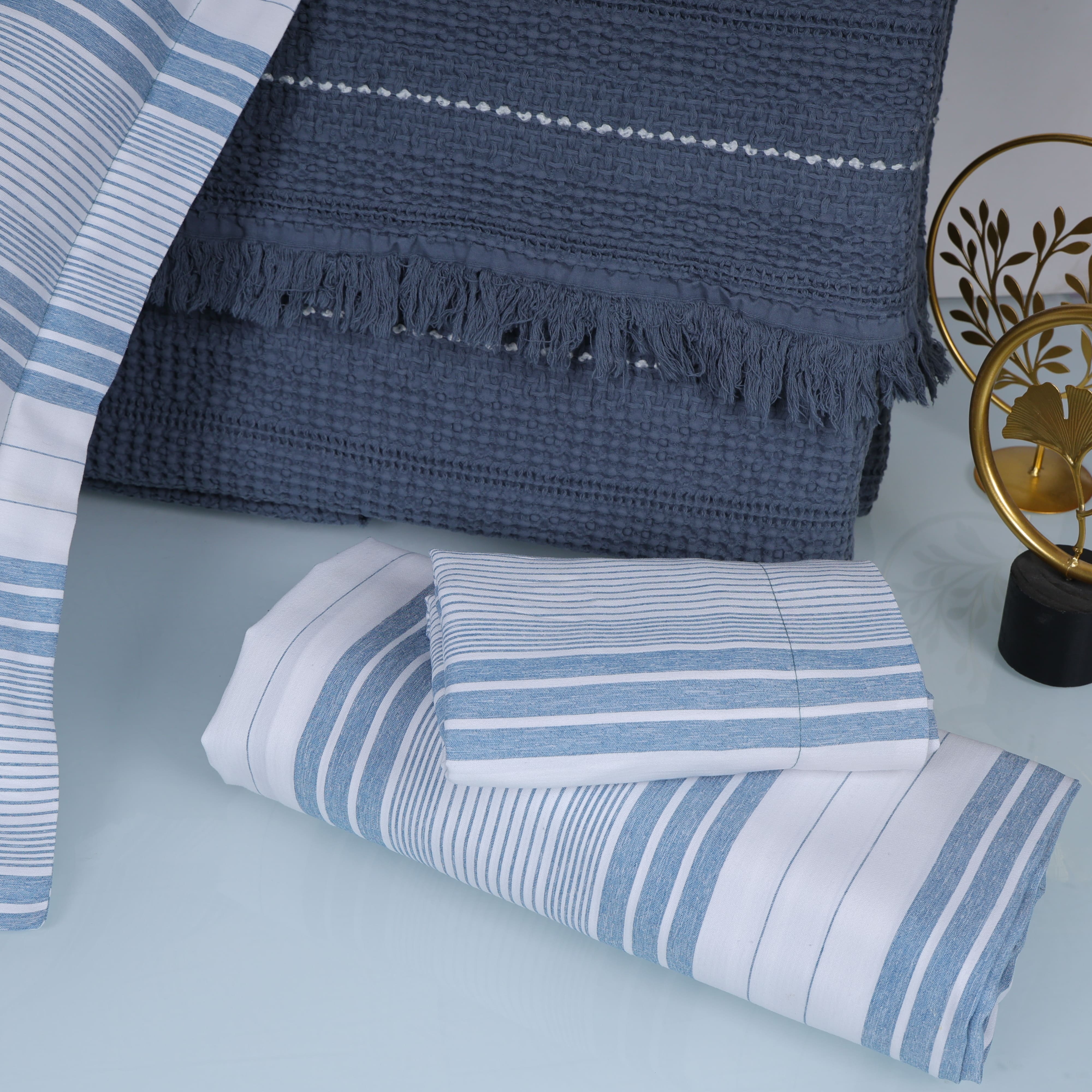 Blue and white striped bedsheet with a textured blue blanket 